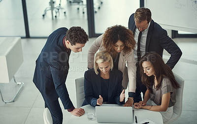 Buy stock photo Shot of a group of colleagues using laptop together during a meeting in a modern office