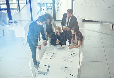 Buy stock photo Shot of a group of colleagues using digital tablet together during a meeting in a modern office