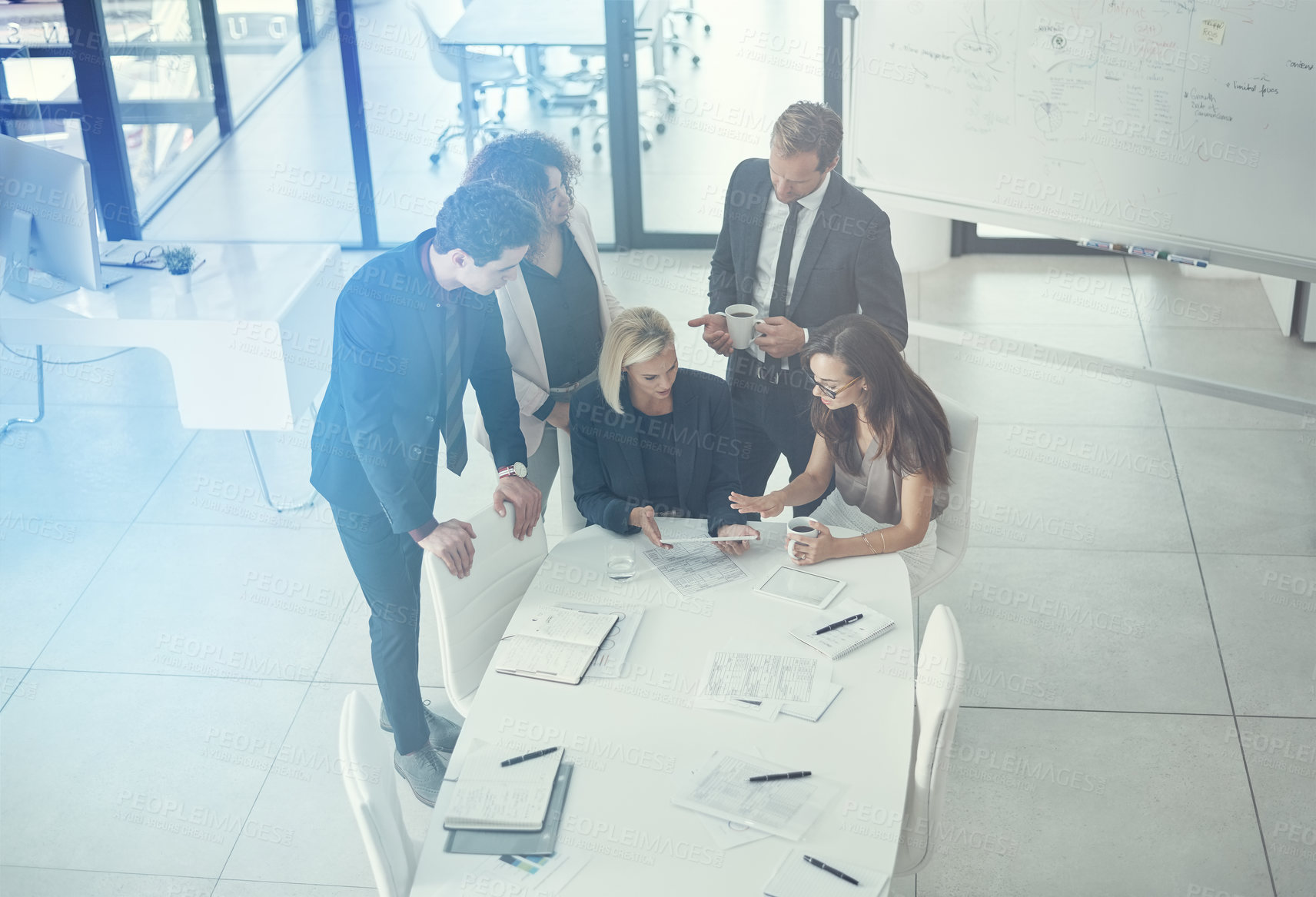 Buy stock photo Shot of a group of colleagues using digital tablet together during a meeting in a modern office