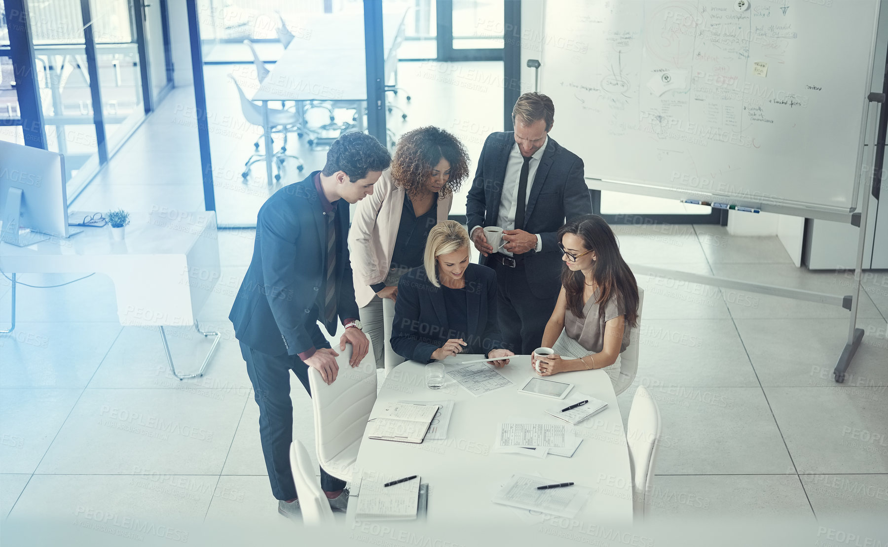 Buy stock photo Shot of a group of colleagues using digital tablet together during a meeting in a modern office