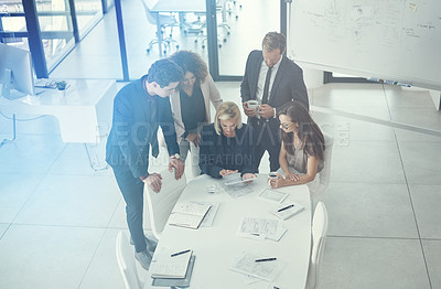 Buy stock photo Shot of a group of colleagues using digital tablet together during a meeting in a modern office