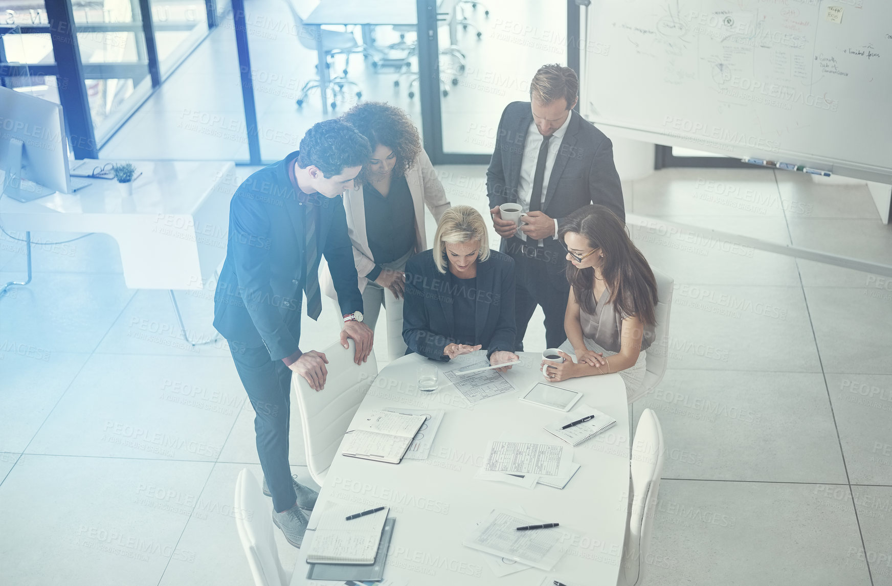 Buy stock photo Shot of a group of colleagues using digital tablet together during a meeting in a modern office