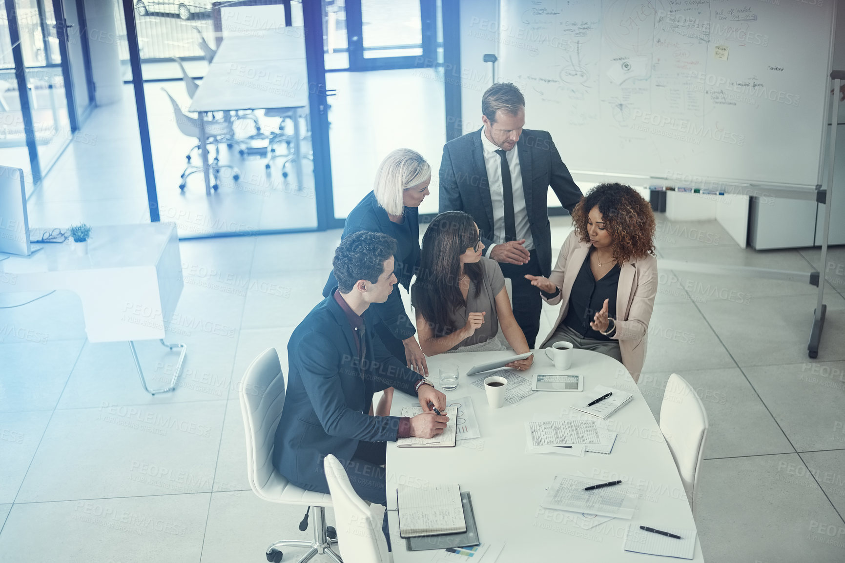 Buy stock photo Shot of a group of colleagues using digital tablet together during a meeting in a modern office