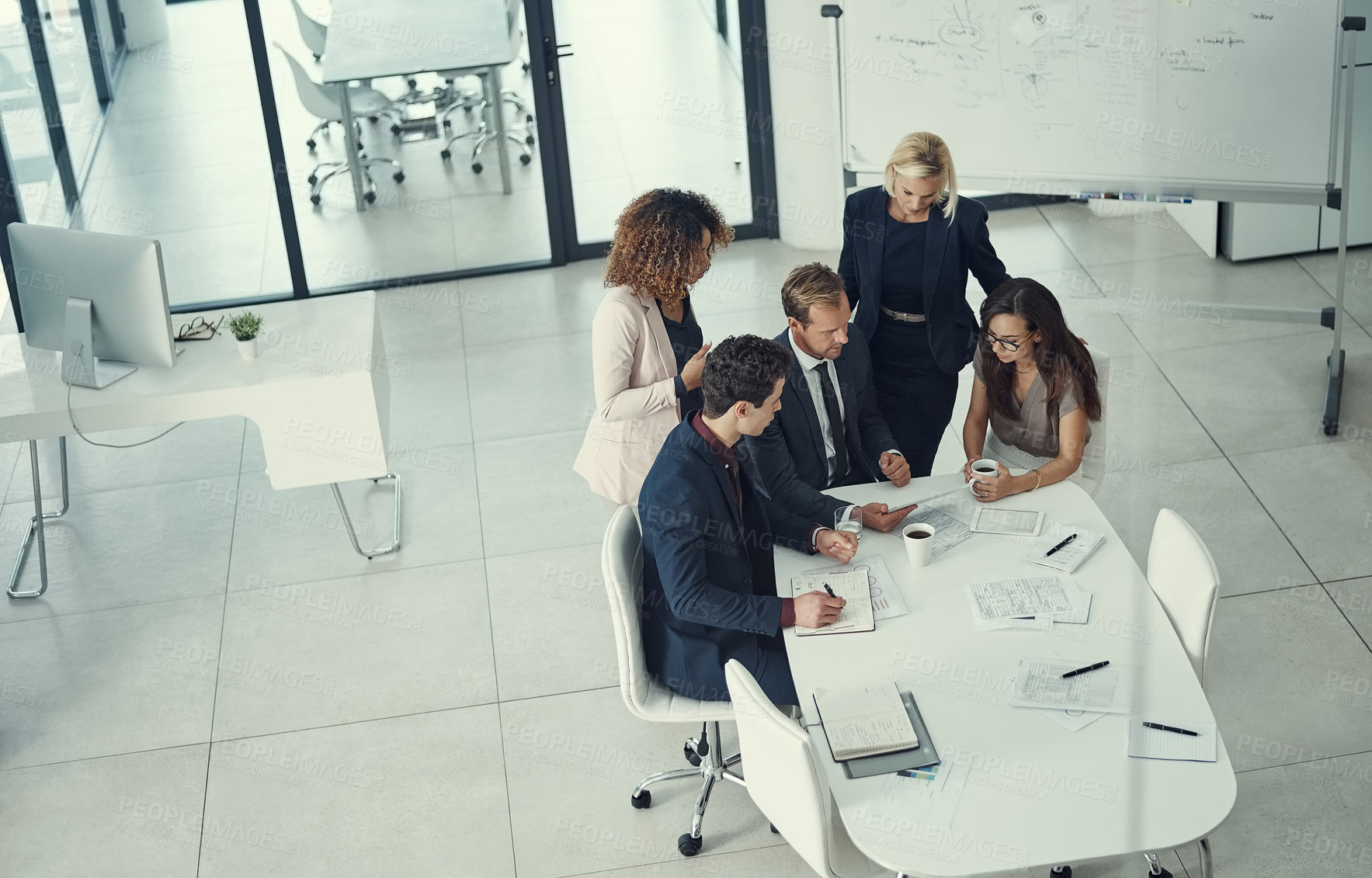 Buy stock photo Shot of a group of colleagues using digital tablet together during a meeting in a modern office