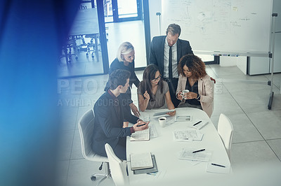 Buy stock photo Shot of a group of colleagues using digital tablet together during a meeting in a modern office