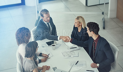 Buy stock photo Shot of two businessmen shaking hands during a meeting in a modern office