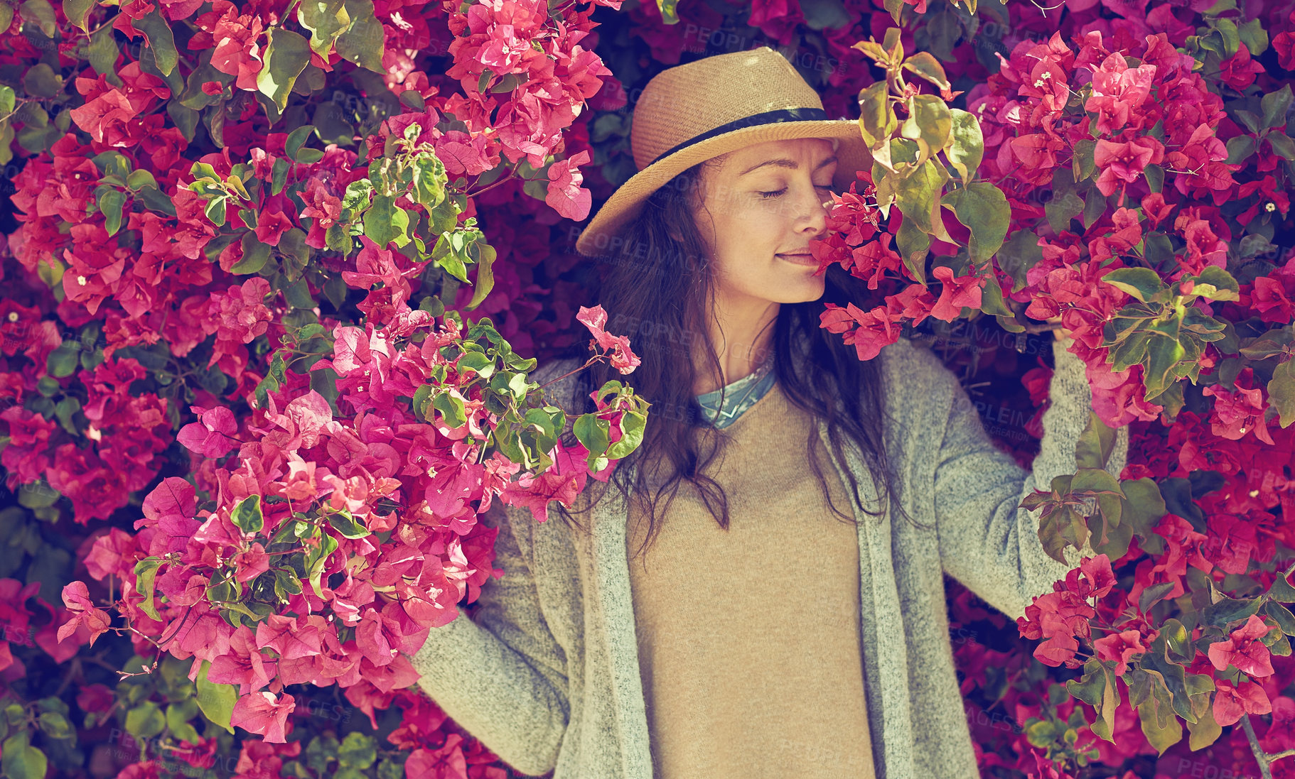 Buy stock photo Shot of an attractive young woman smelling the scent of a flowering bush