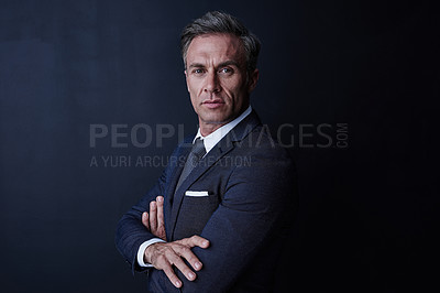 Buy stock photo Studio portrait of a confident and mature businessman standing against a dark background