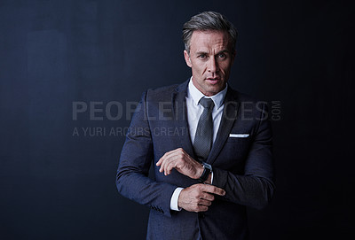 Buy stock photo Studio portrait of a stylish and mature businessman standing against a dark background