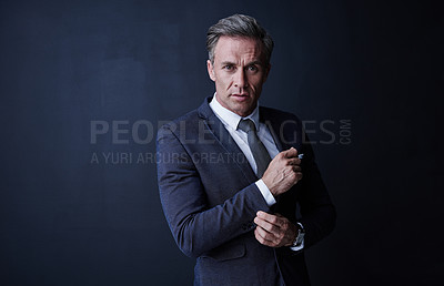 Buy stock photo Studio portrait of a stylish and mature businessman standing against a dark background