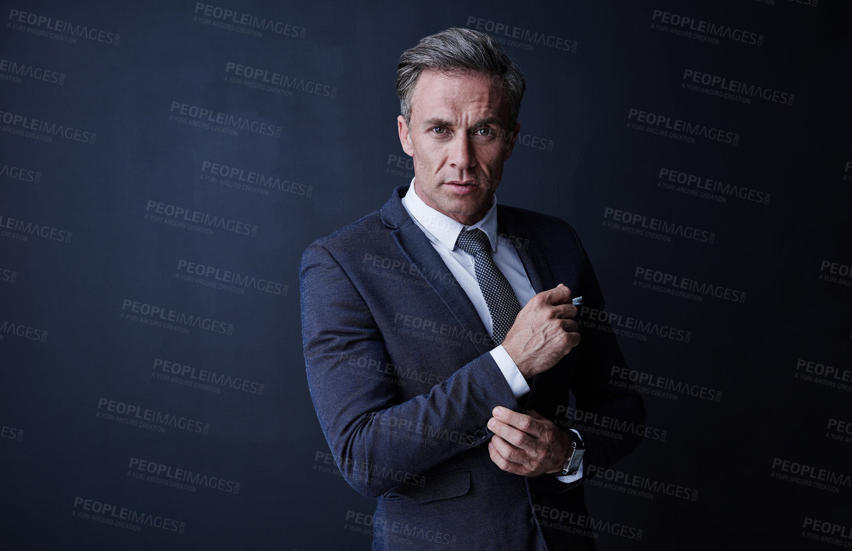 Buy stock photo Studio portrait of a stylish and mature businessman standing against a dark background