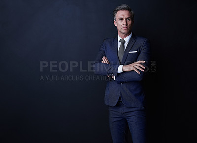 Buy stock photo Studio shot of a confident and mature businessman standing against a dark background