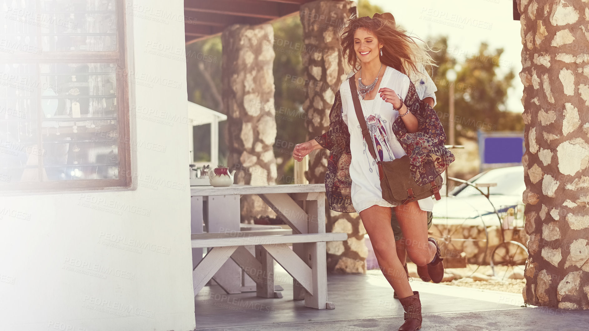 Buy stock photo Shot of a happy young couple running around a roadside shop together