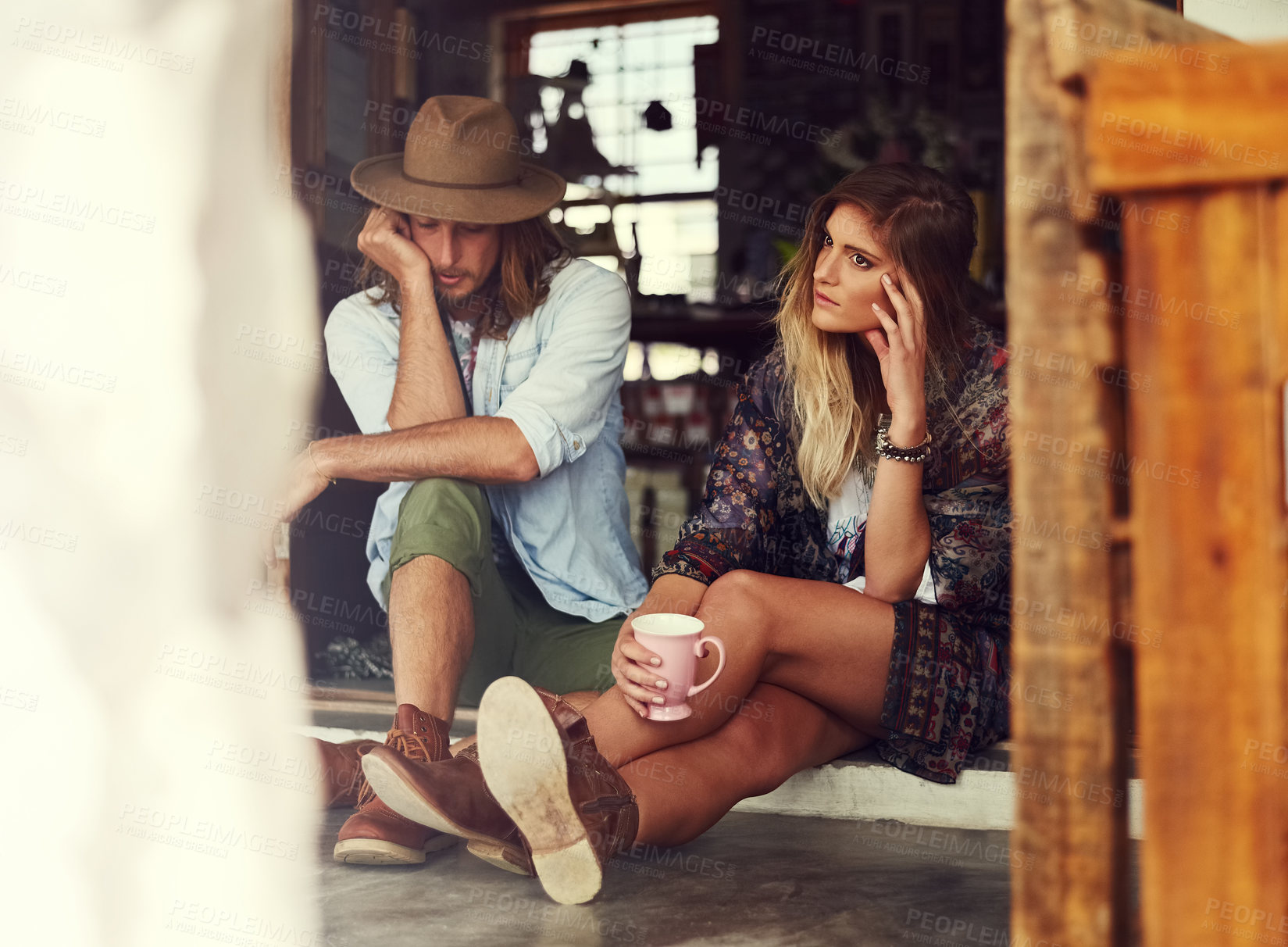 Buy stock photo Shot of an affectionate young couple sitting in the doorway of a roadside shop