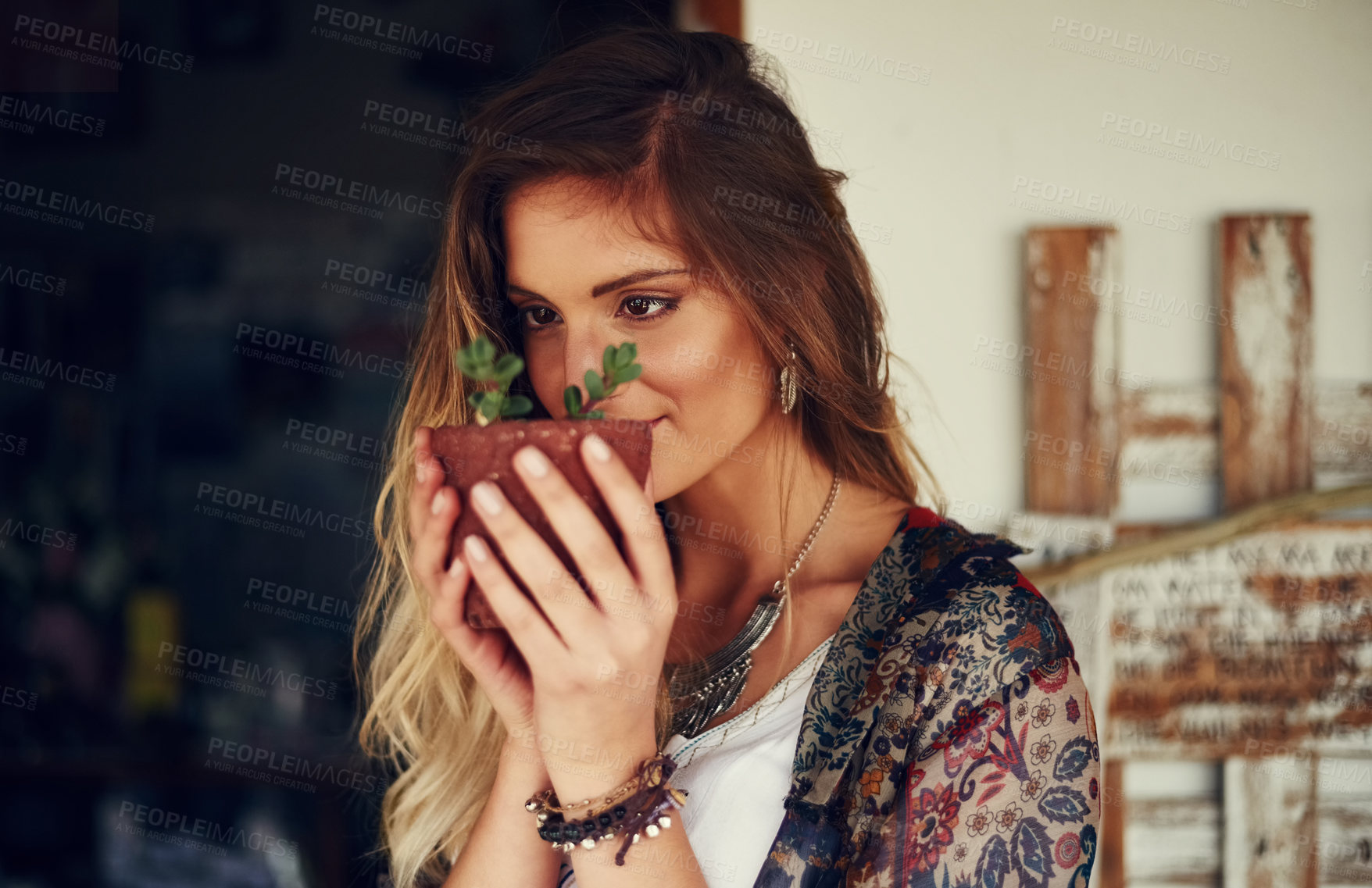 Buy stock photo Shot of a free spirited young woman admiring a pot plant in her hands