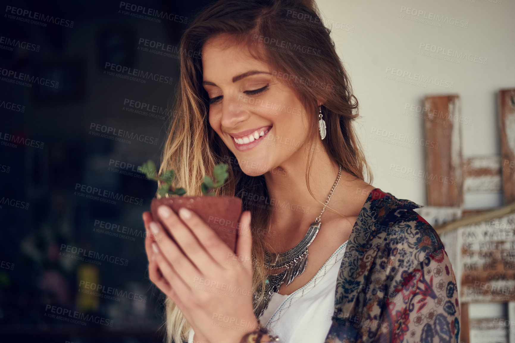 Buy stock photo Shot of a free spirited young woman admiring a pot plant in her hands