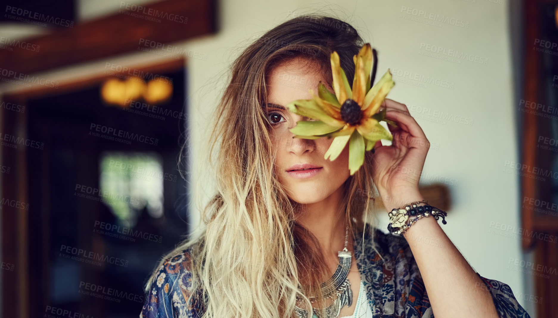 Buy stock photo Portrait of a free spirited young woman posing at a roadside shop with a flower