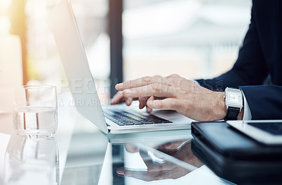 Buy stock photo Shot of an unidentifiable businessman working on a laptop in an office