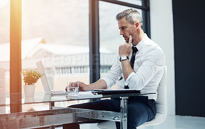 Buy stock photo Shot of a corporate businessman working on a laptop in an office