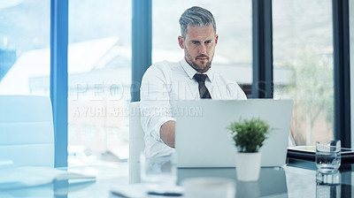 Buy stock photo Shot of a corporate businessman working on a laptop in an office