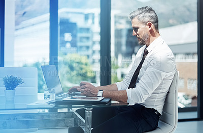 Buy stock photo Shot of a corporate businessman working on a laptop in an office