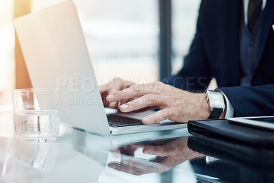 Buy stock photo Shot of an unidentifiable businessman working on a laptop in an office