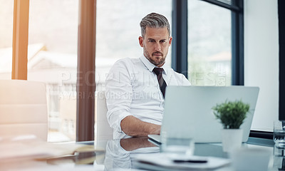 Buy stock photo Shot of a corporate businessman working on a laptop in an office