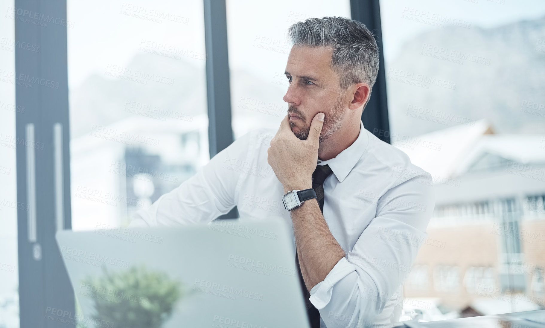 Buy stock photo Shot of a corporate businessman looking thoughtful while working in an office