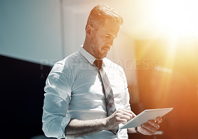 Buy stock photo Shot of a corporate businessman using a digital tablet in an office