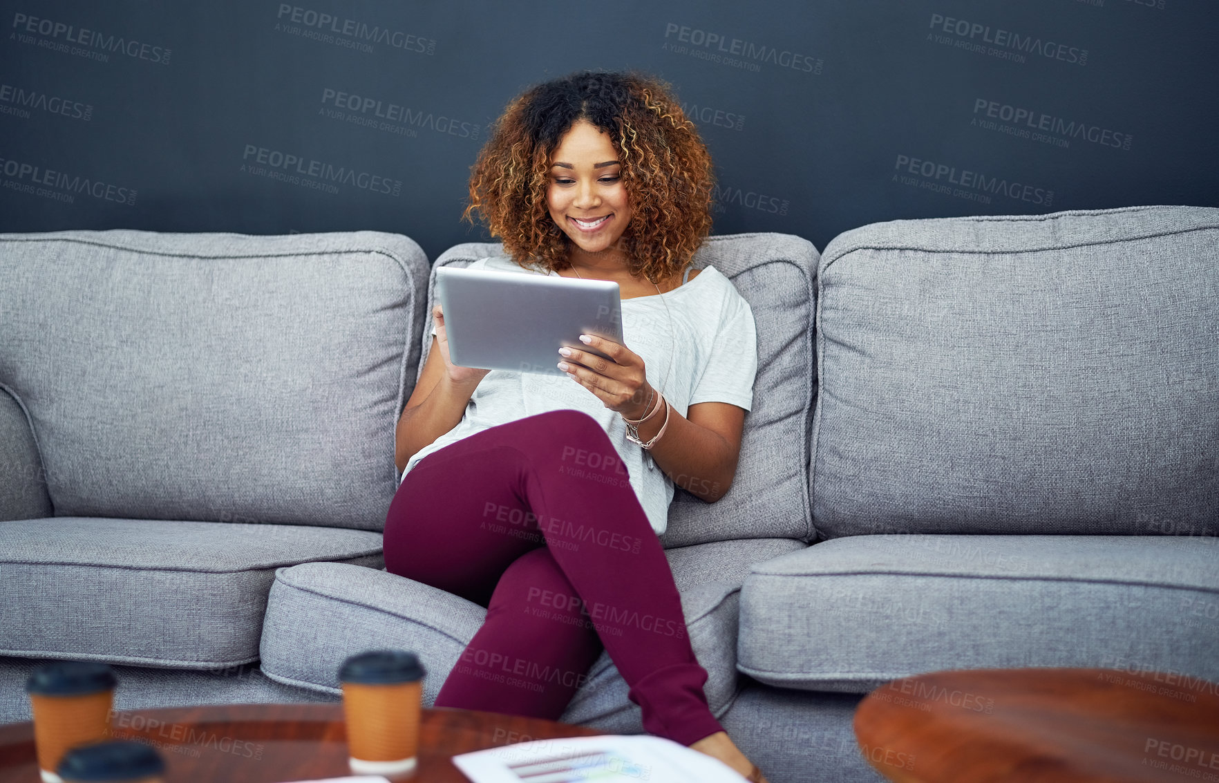 Buy stock photo Shot of a young businesswoman using a digital tablet on the sofa in a modern office