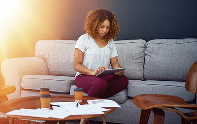 Buy stock photo Shot of a young businesswoman using a digital tablet on the sofa in a modern office
