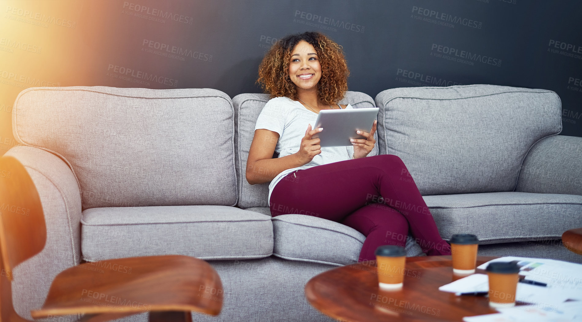 Buy stock photo Shot of a young businesswoman using a digital tablet on the sofa in a modern office