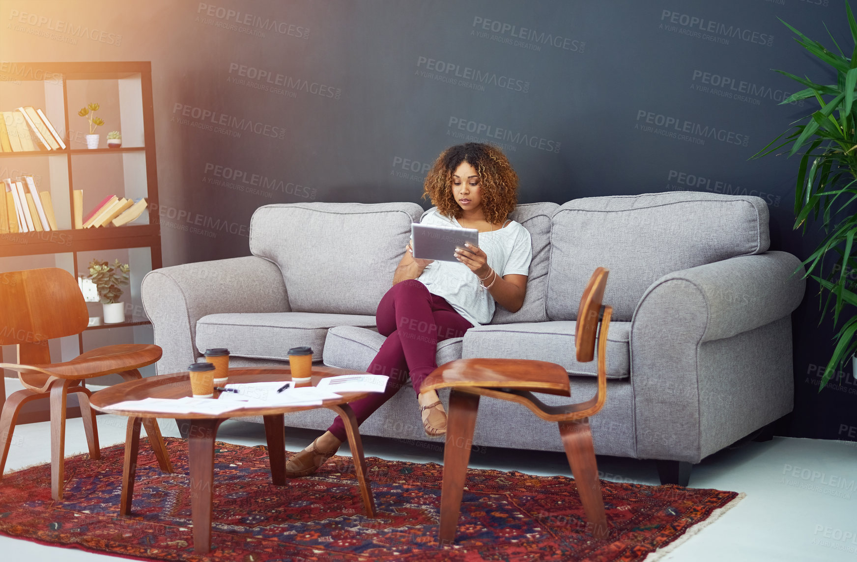 Buy stock photo Shot of a young businesswoman using a digital tablet on the sofa in a modern office