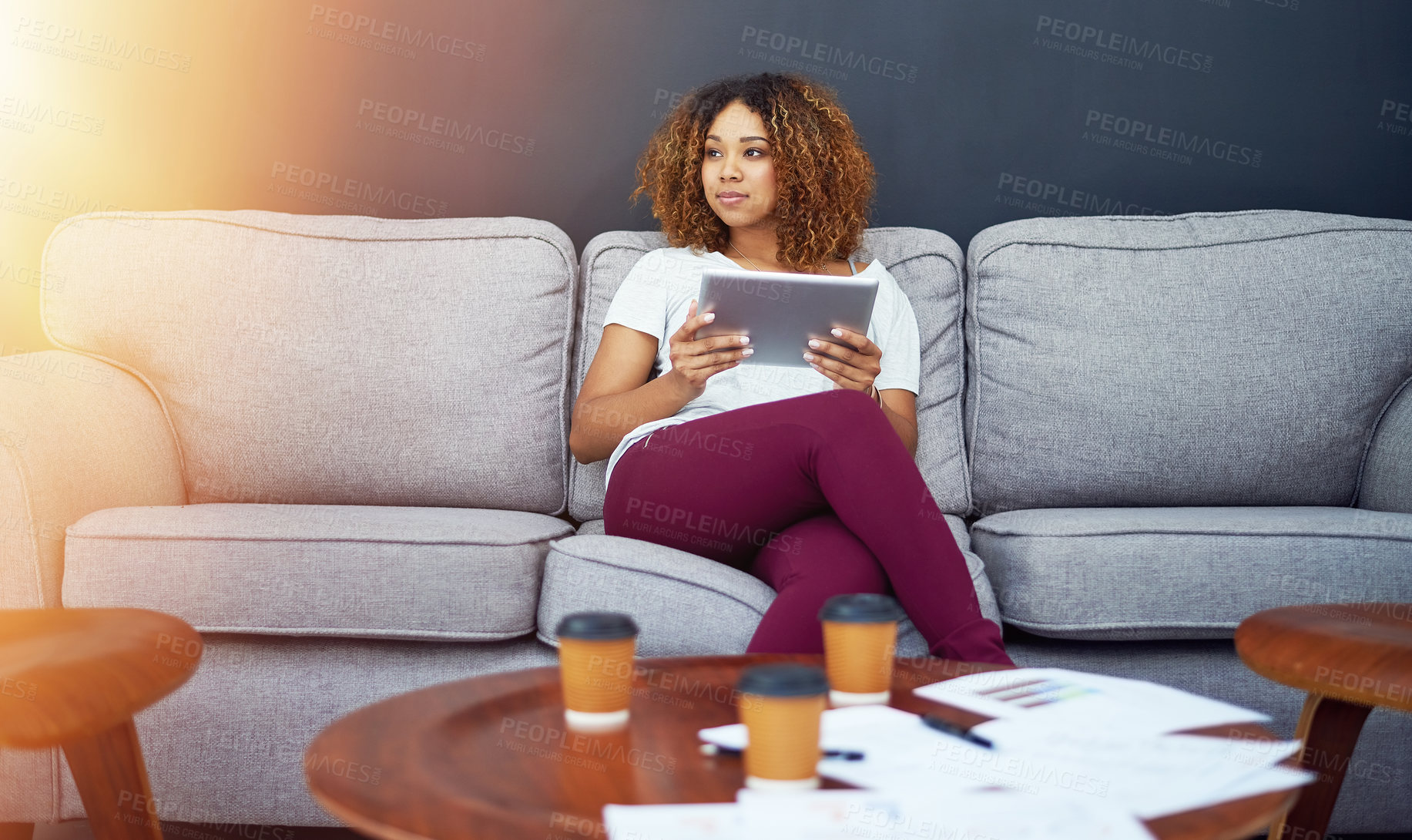 Buy stock photo Shot of a young businesswoman using a digital tablet on the sofa in a modern office