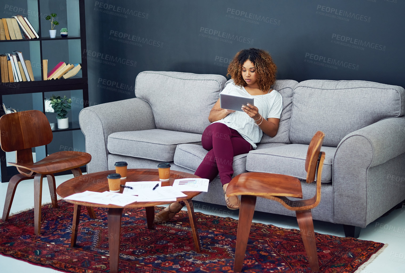 Buy stock photo Shot of a young businesswoman using a digital tablet on the sofa in a modern office