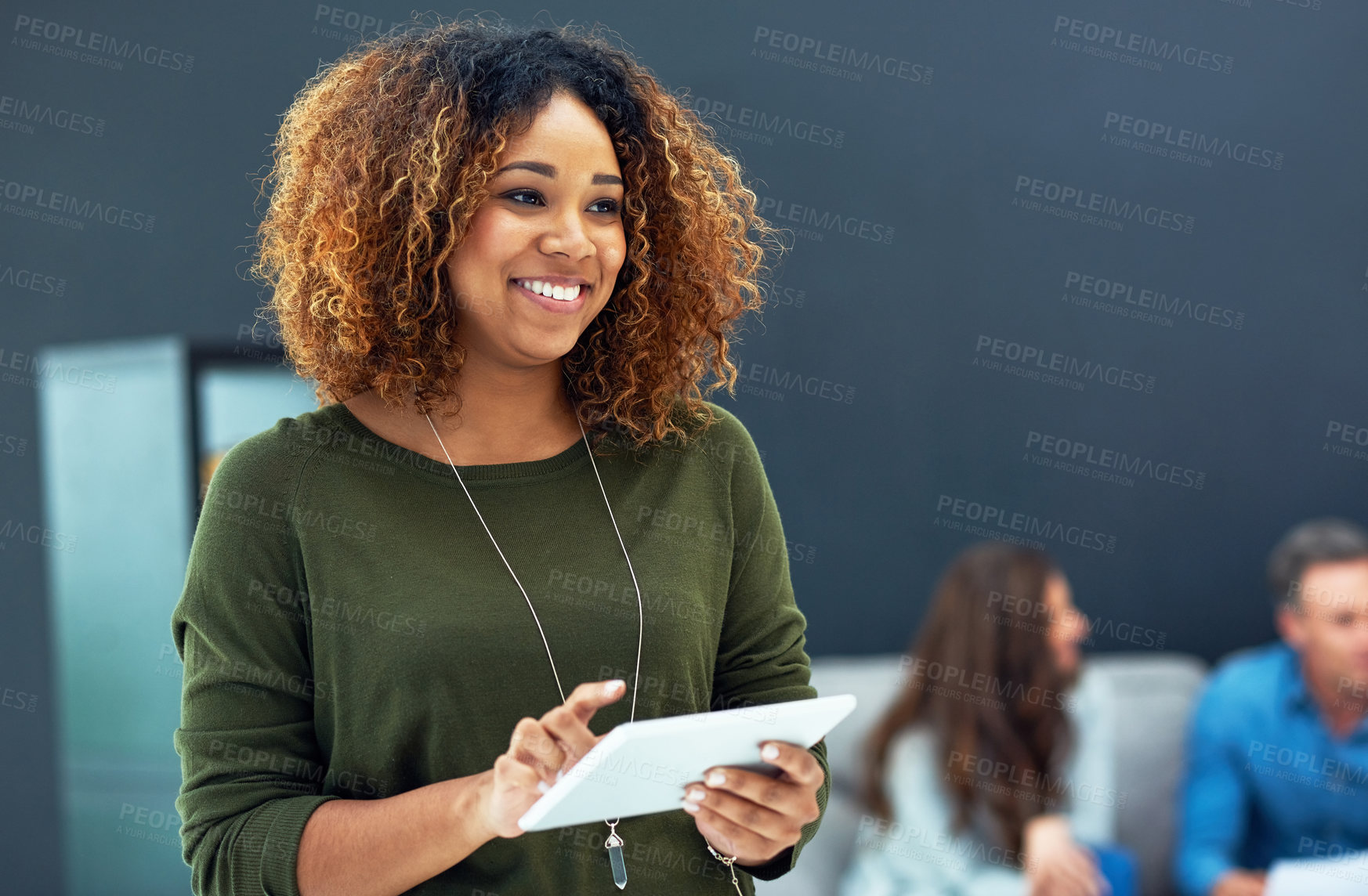 Buy stock photo Shot of a young businesswoman using a digital tablet with her team in the background