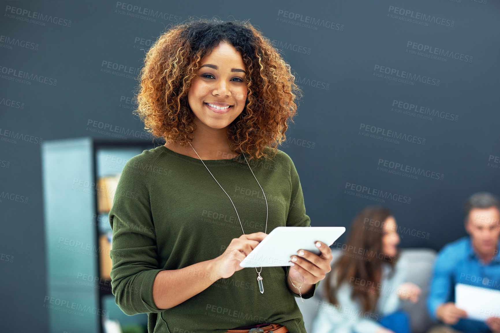 Buy stock photo Portrait of a young businesswoman using a digital tablet with her team in the background