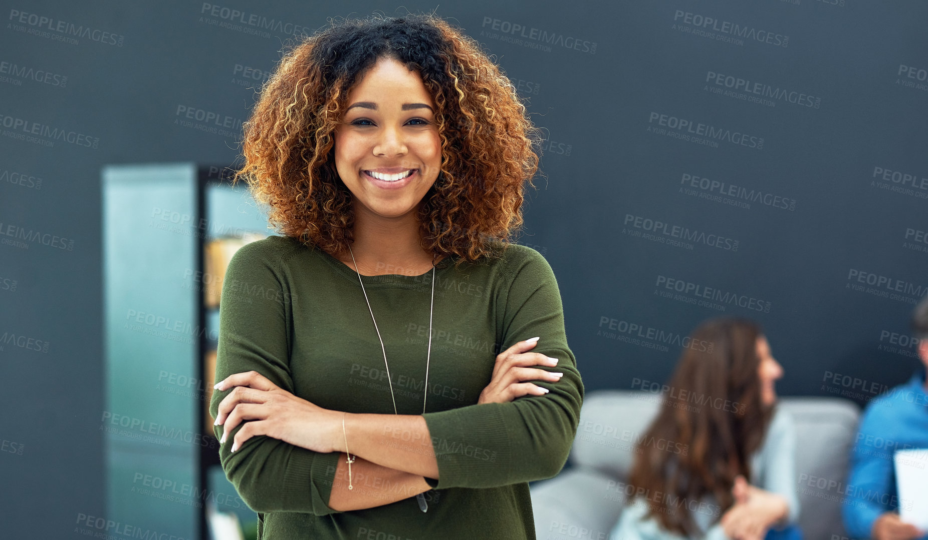 Buy stock photo Portrait of a confident young businesswoman with her team blurred in the background