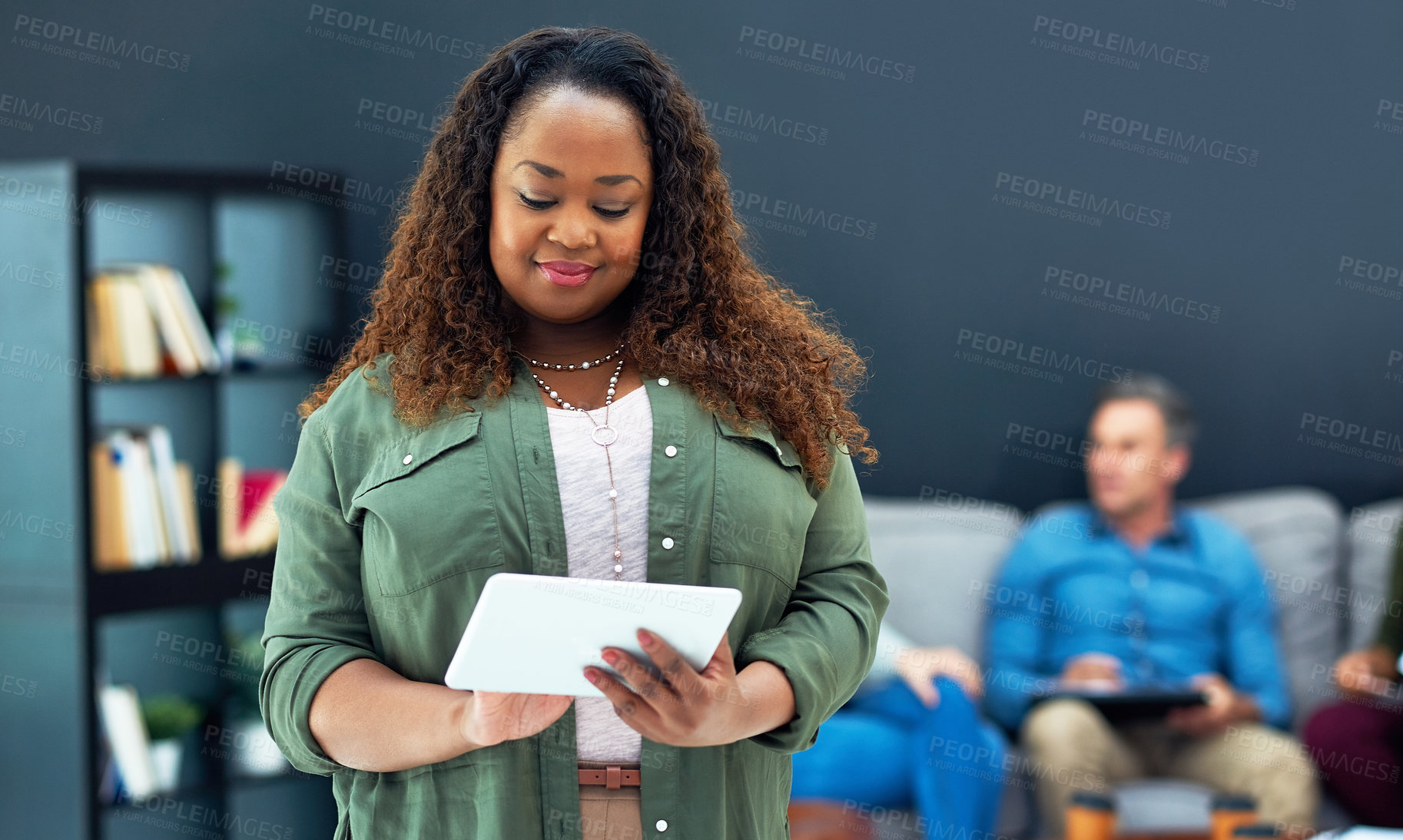 Buy stock photo Shot of a young businesswoman using a digital tablet with her team in the background