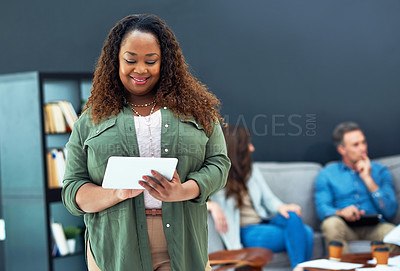 Buy stock photo Shot of a young businesswoman using a digital tablet with her team in the background