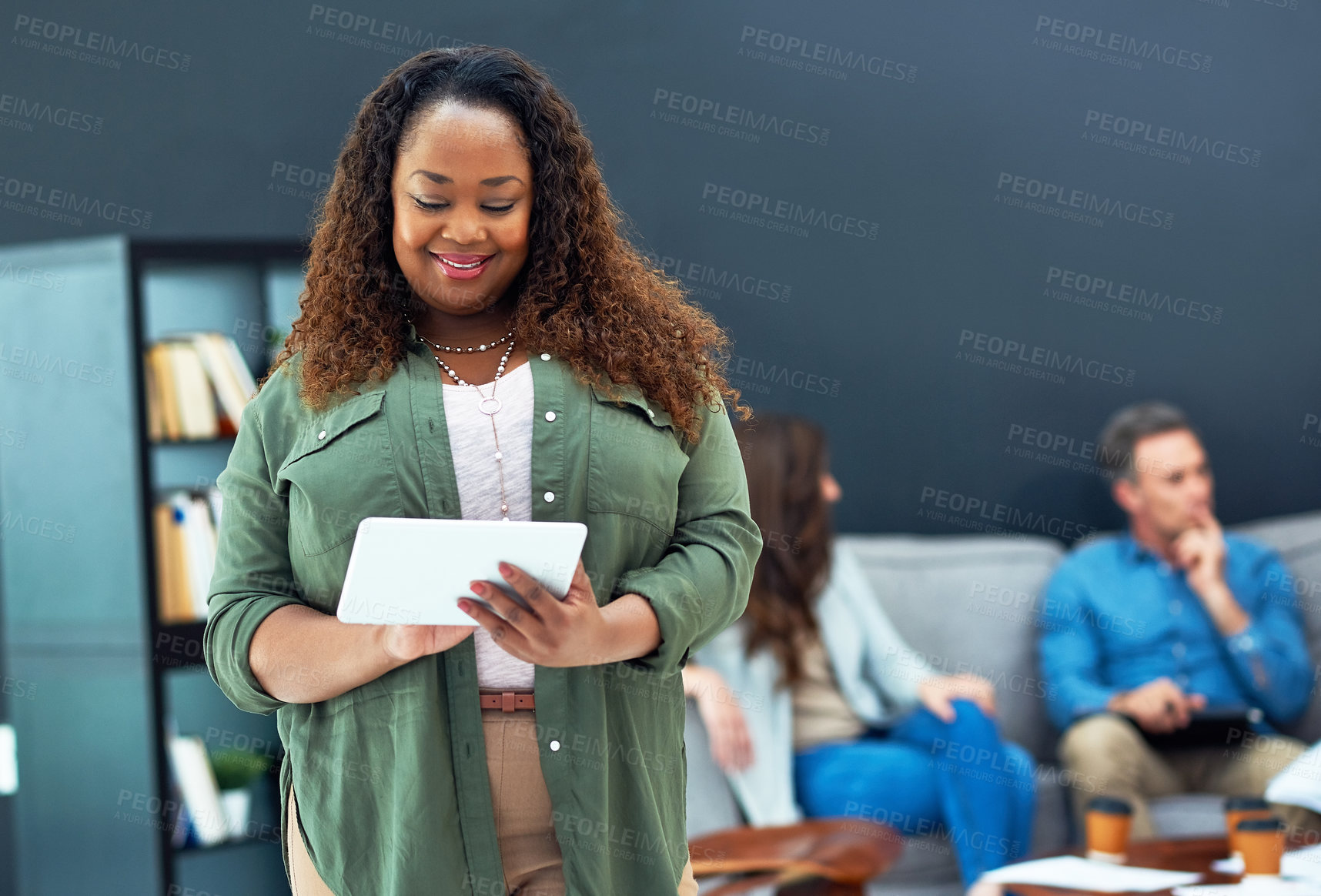 Buy stock photo Shot of a young businesswoman using a digital tablet with her team in the background