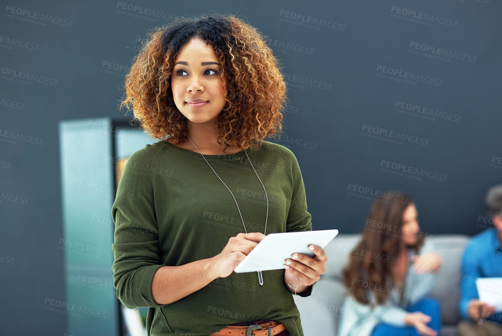 Buy stock photo Shot of a young businesswoman using a digital tablet with her team in the background