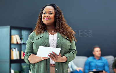 Buy stock photo Shot of a young businesswoman using a digital tablet with her team in the background