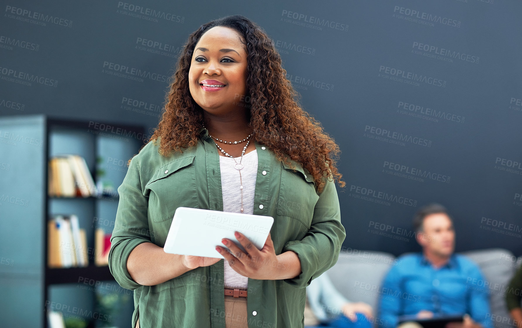 Buy stock photo Shot of a young businesswoman using a digital tablet with her team in the background