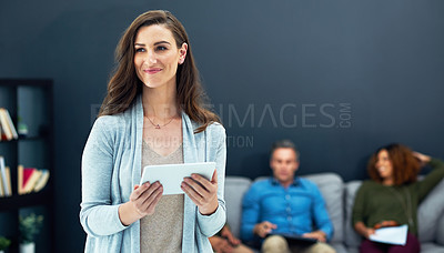 Buy stock photo Shot of a young businesswoman using a digital tablet with her team in the background