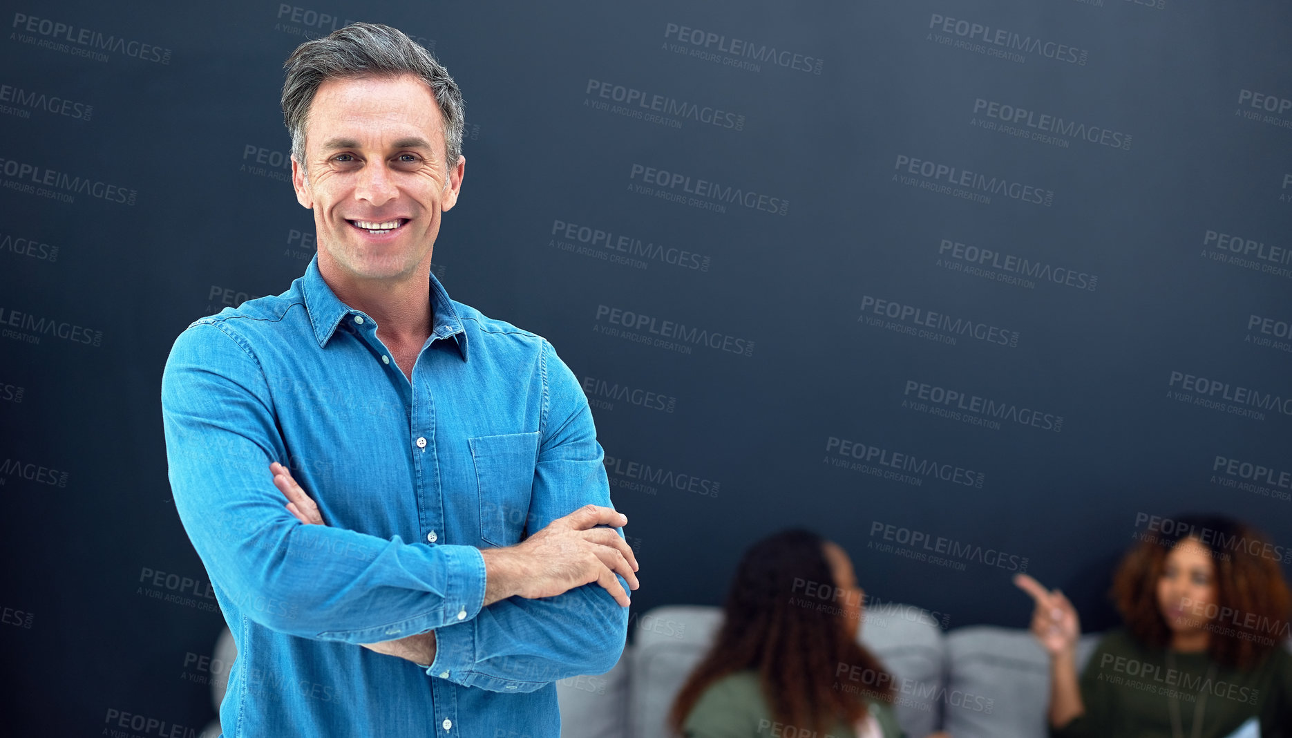 Buy stock photo Portrait of a confident mature businessman with his team blurred in the background