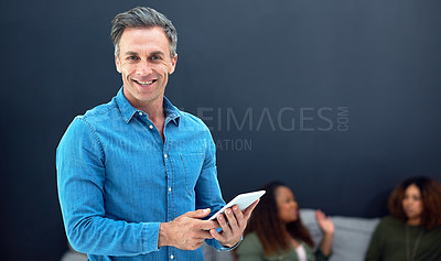 Buy stock photo Portrait of a mature businessman using a digital tablet with his team in the background