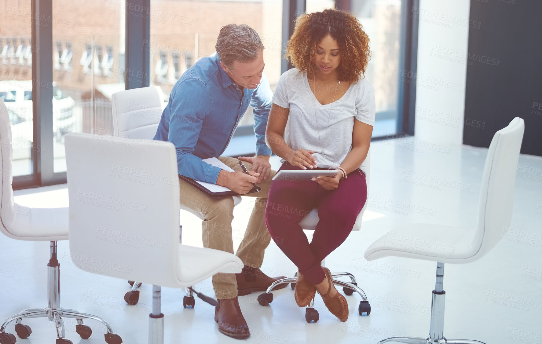 Buy stock photo Shot of two colleagues using a digital tablet together in a modern office