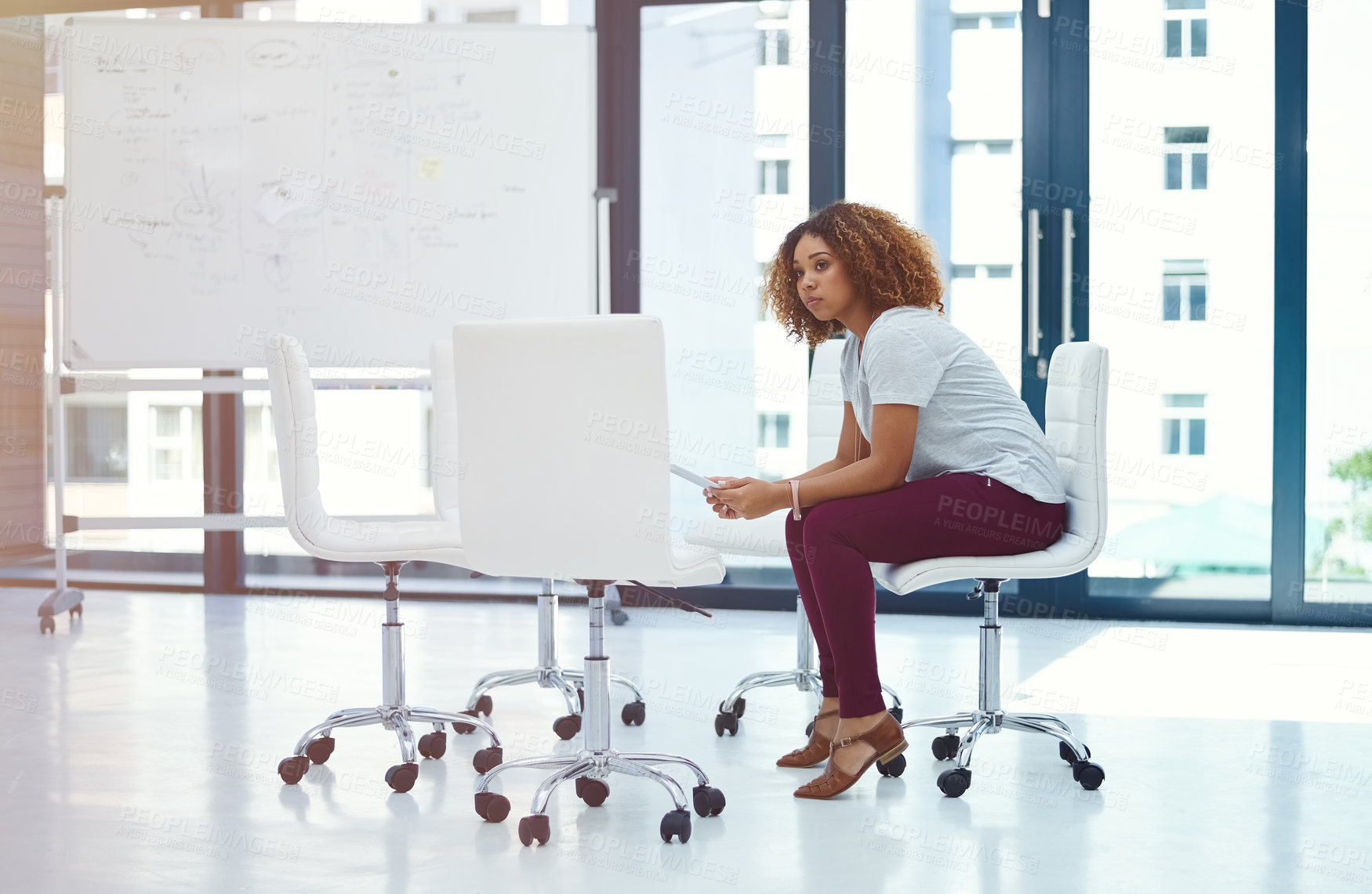 Buy stock photo Shot of a thoughtful young businesswoman using a digital tablet in a modern office