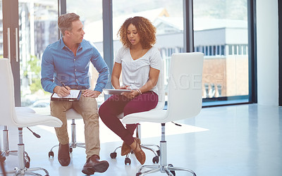Buy stock photo Shot of two colleagues using a digital tablet together in a modern office